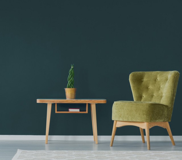 a bright green chair and side table infront of a big bold wall painted with forest green paint