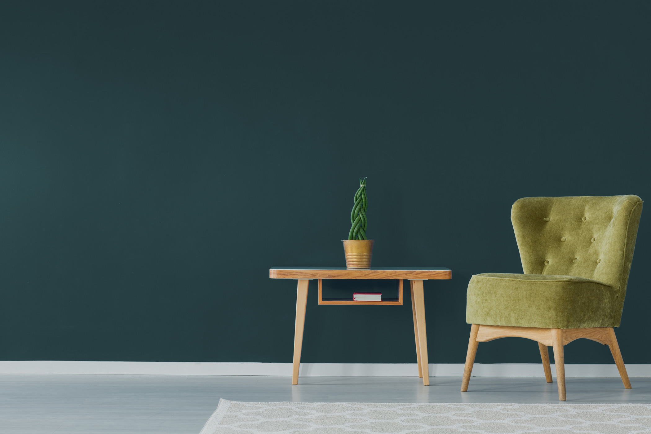 a bright green chair and side table infront of a big bold wall painted with forest green paint