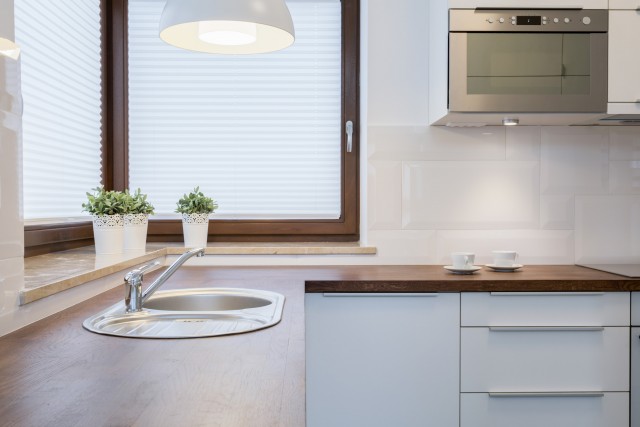 a kitchen corner with bright lights and a roller shaded window covering